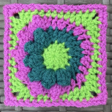 Brightly coloured crochet granny square with a popcorn stitch texture