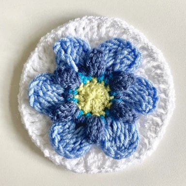 Round 7. Pale blue crochet granny square flower with white circular border