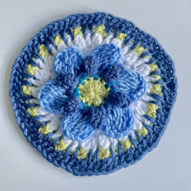 Completed crochet granny square in pale blue with white and blue border