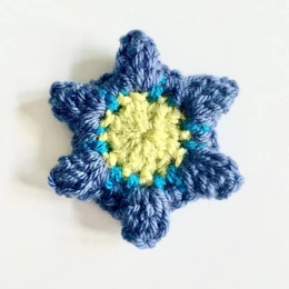 Round 3. Crochet flower for granny square blanket. Pale green circular centre, mid blue petals.
