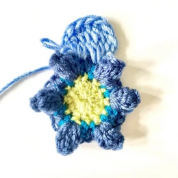 Round 4. crochet flower. Pale green centre, mid blue border, crocheting first pale blue petal