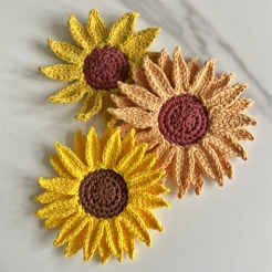 3 different crochet sunflowers placed on a white table