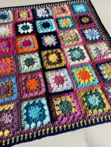 cosy scrap yarn crochet blanket laid out - multi -coloured