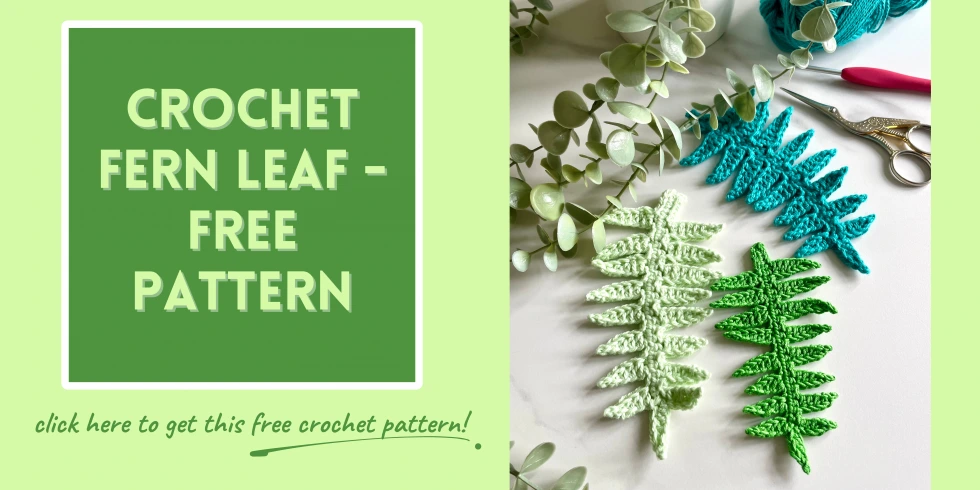A button to take readers to the crochet fern leaf free pattern. It features 3 crochet fern leaves in different shades of green with foliage in the background and a pair of scissors and a crochet hook
